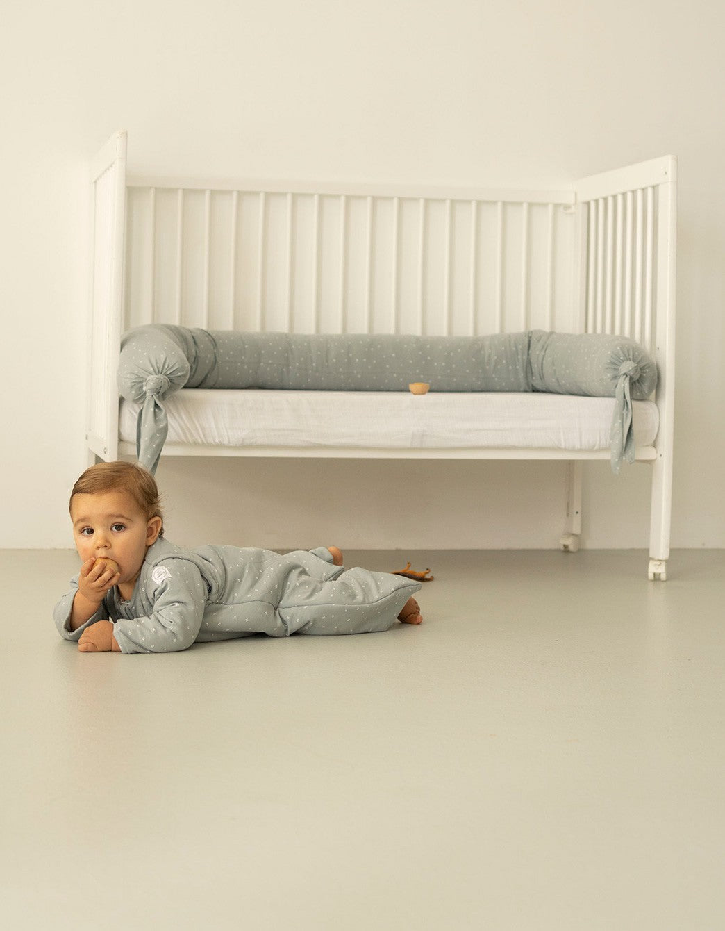Cojín protector para cuna tipo chichonera Hojas Blancas colocado en cama infantil.