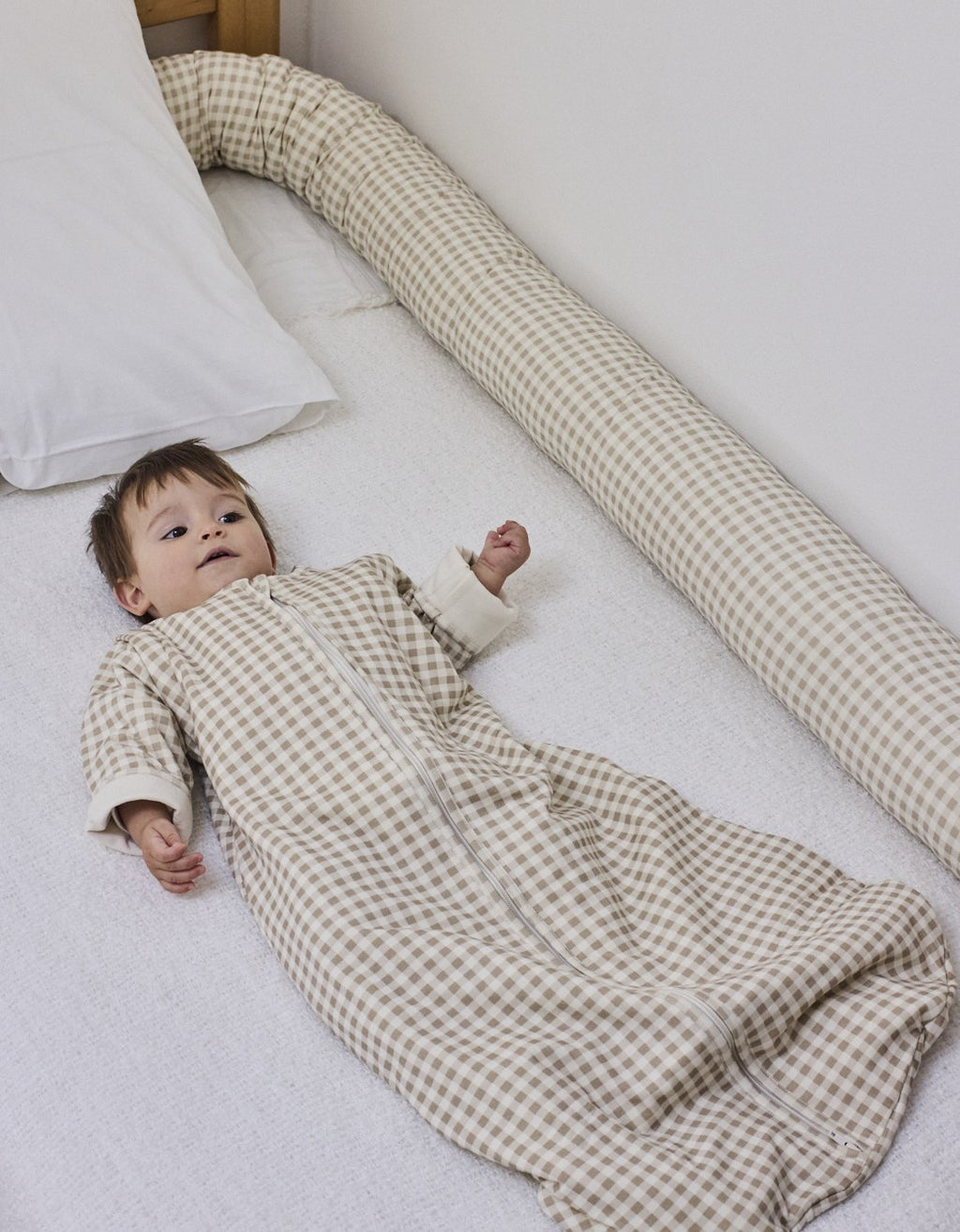 Cojín protector Vichy Sand en la cama con el bebé descansando, en algodón orgánico.