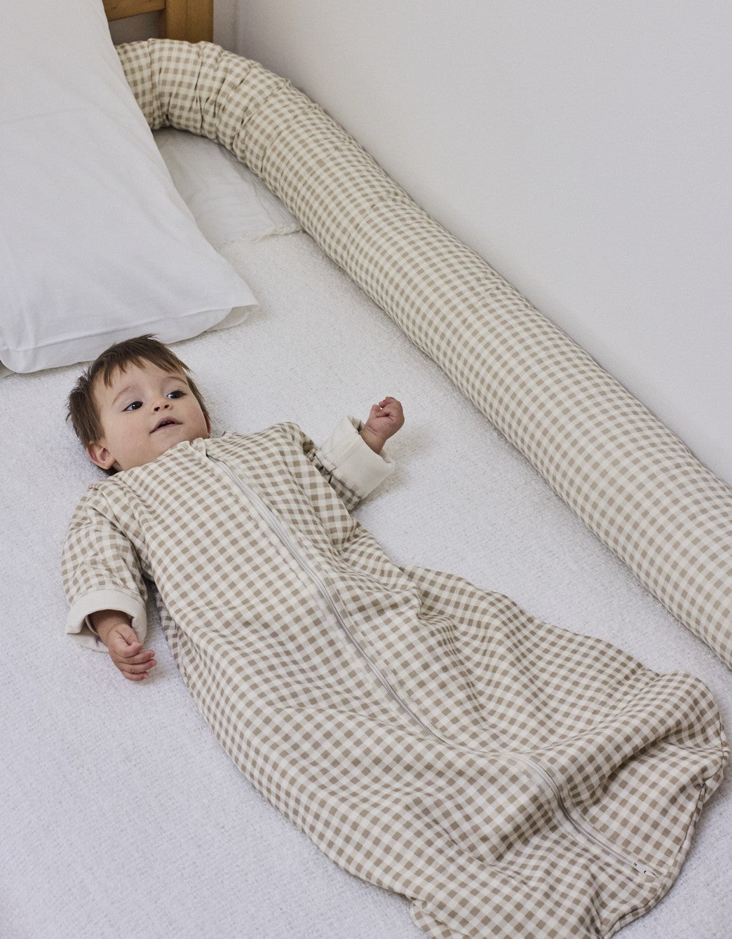 Cojín protector Vichy Sand en la cama con el bebé descansando, en algodón orgánico.