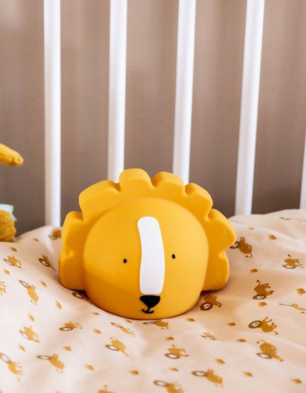Luz de noche infantil Mr Lion con diseño de león colocada sobre una cama infantil, ideal para decorar y acompañar el descanso de bebés y niños.