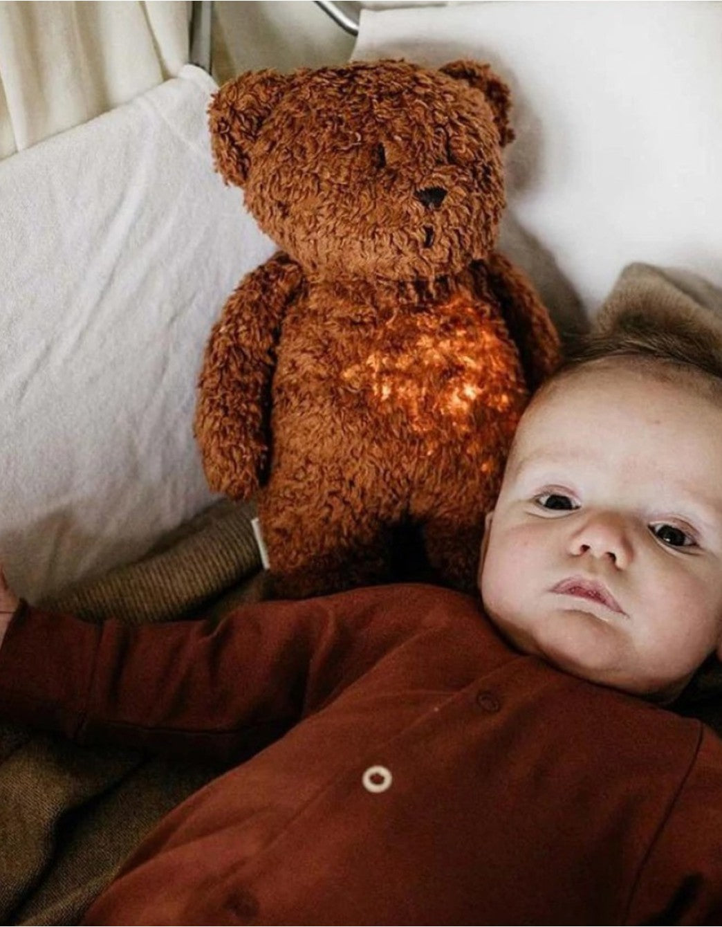 Bebé junto a osito marrón con luz y música, un peluche quitamiedos diseñado para aportar calma, confort y acompañamiento durante el día y la noche.