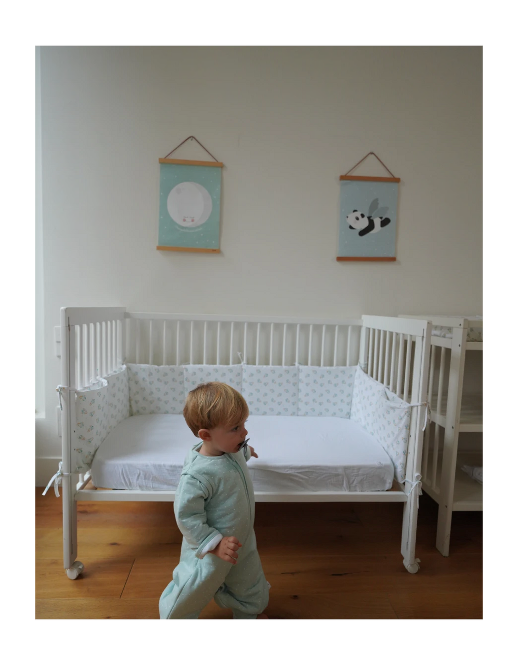Protector de cuna Leaves de algodón orgánico con estampado de hojas, instalado en cuna infantil para proteger los laterales y crear un entorno seguro y confortable para el bebé.