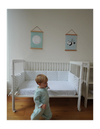 Protector de cuna Leaves de algodón orgánico con estampado de hojas, instalado en cuna infantil para proteger los laterales y crear un entorno seguro y confortable para el bebé.