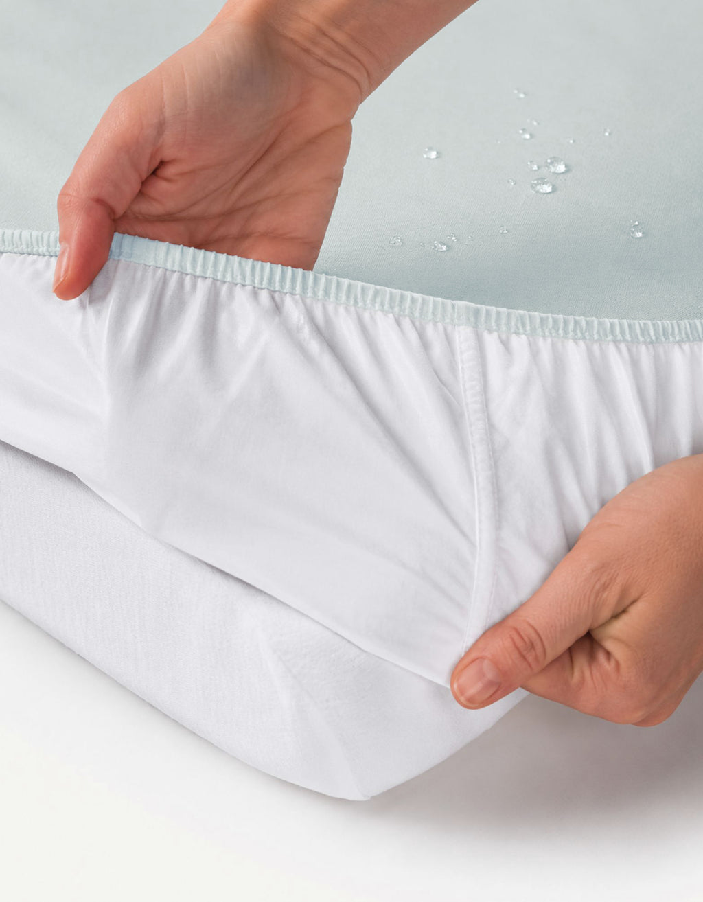 Detalle del ajuste elástico de la sábana bajera con protector impermeable para cuna 70x140 cm color agua.