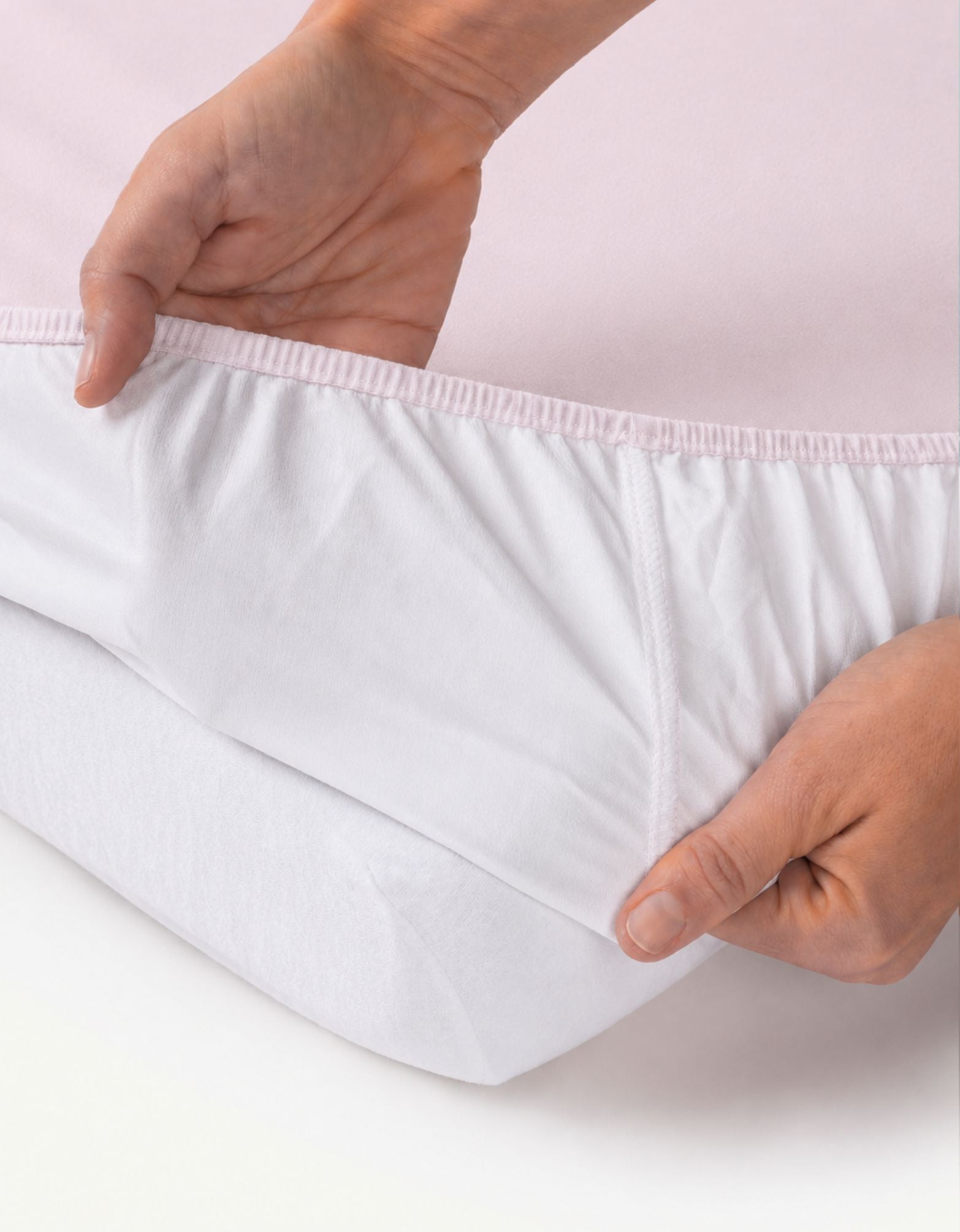 Detalle del ajuste elástico de la sábana bajera con protector impermeable para cuna 70x140 cm color rosa.