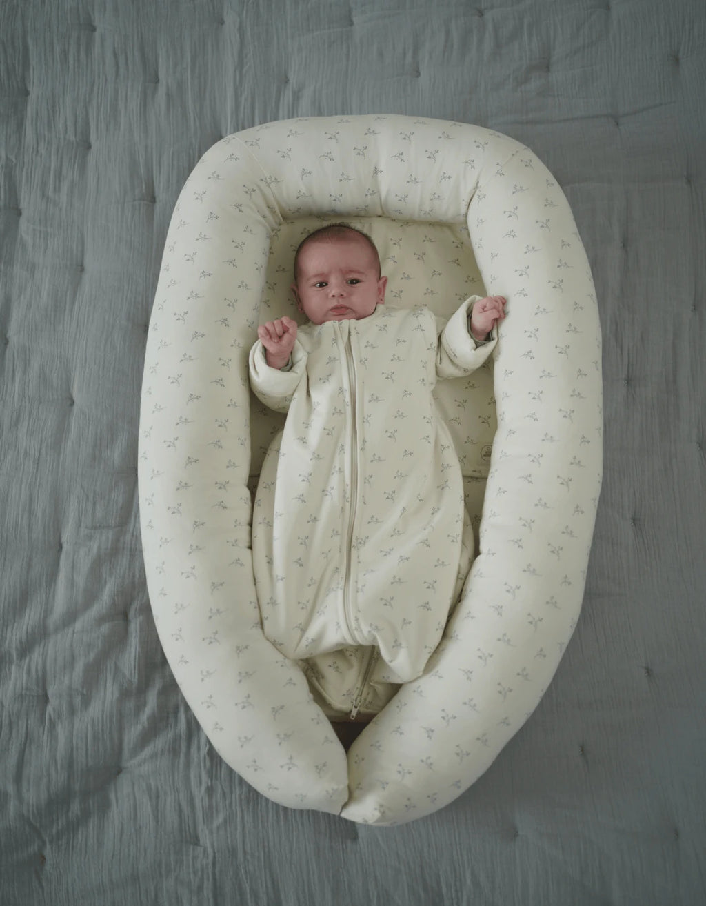 Sábana salvababas Olive Cream de algodón orgánico en nido para bebé con estampado de ramas de olivo y tejido suave absorbente.