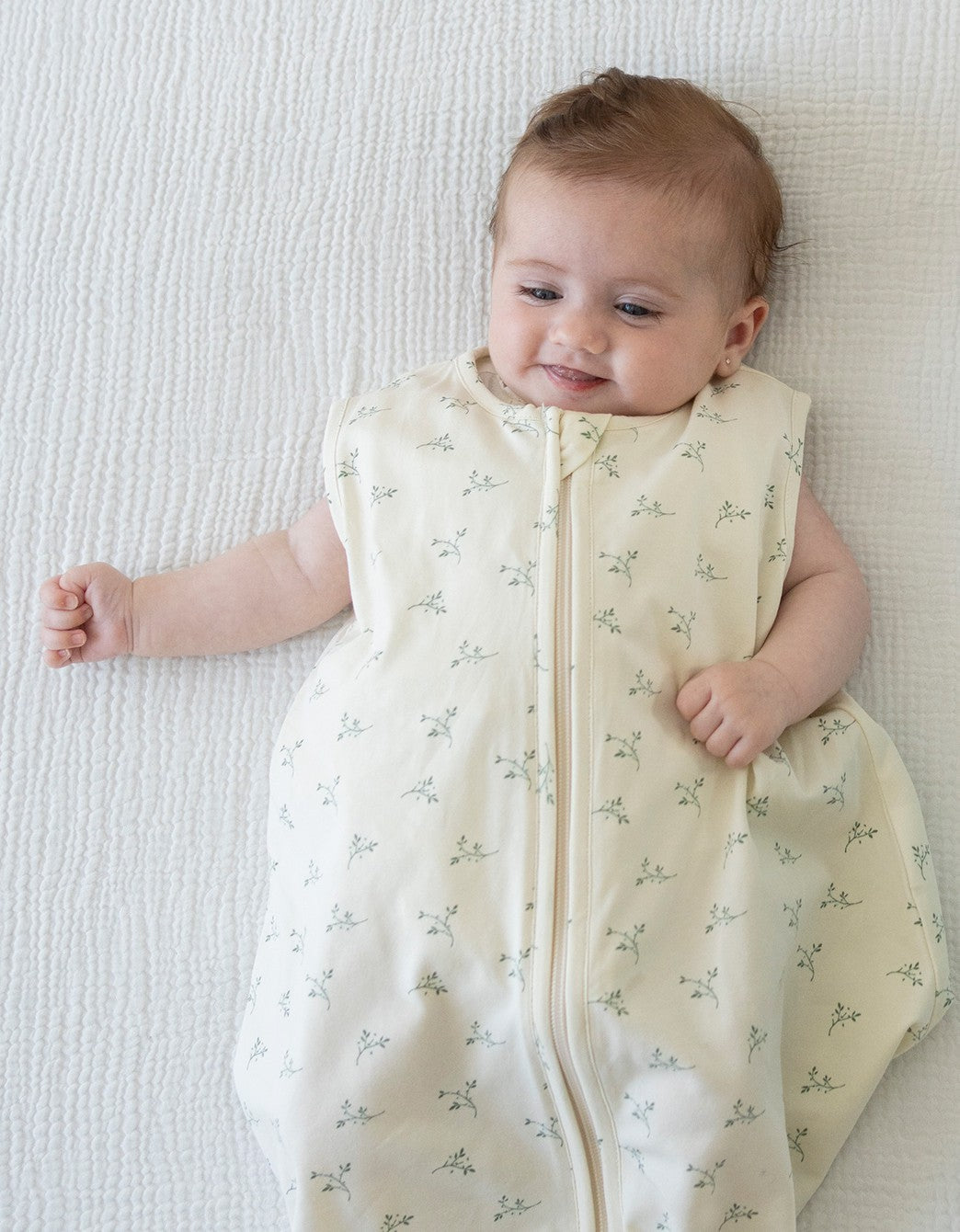 Bebé sonriendo con saco de dormir Olive Cream TOG 0,5 de algodón orgánico