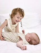 Bebé con saco de dormir Vichy Sand TOG 0,5 compartiendo un momento con su hermano.
